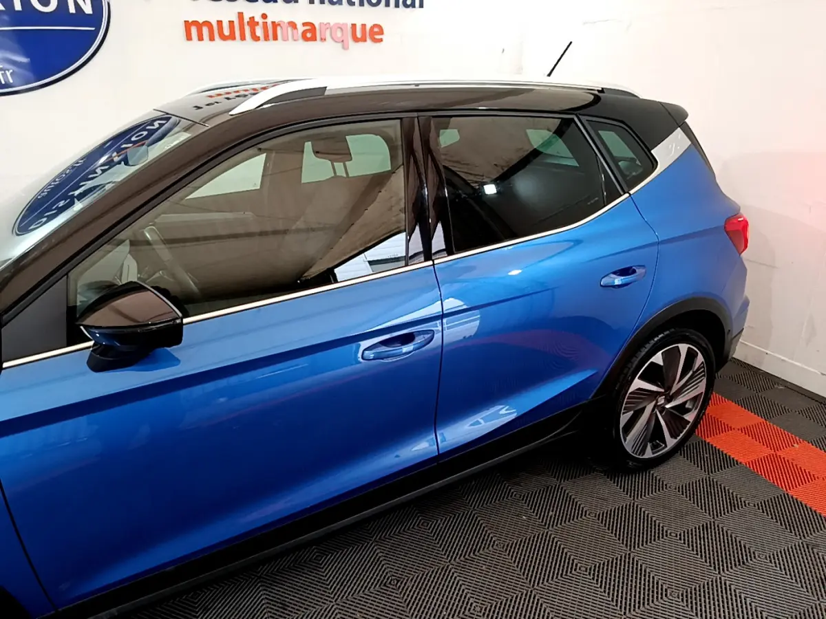 Vue latérale côté gauche du SEAT Arona bleu 2022 avec toit noir et jantes alliage distinctives.