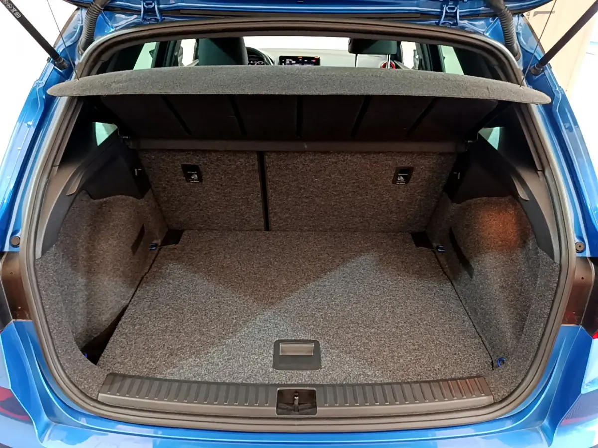 Coffre ouvert vu de l'arrière d'un SEAT Arona bleu 2022, espace de rangement avec tablette amovible.