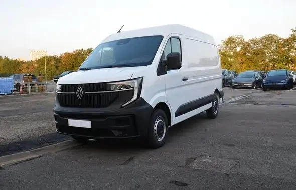 Vue 3/4 avant droite du Renault Master blanc 2025 avec calandre noire et feux LED distinctifs sur parking.