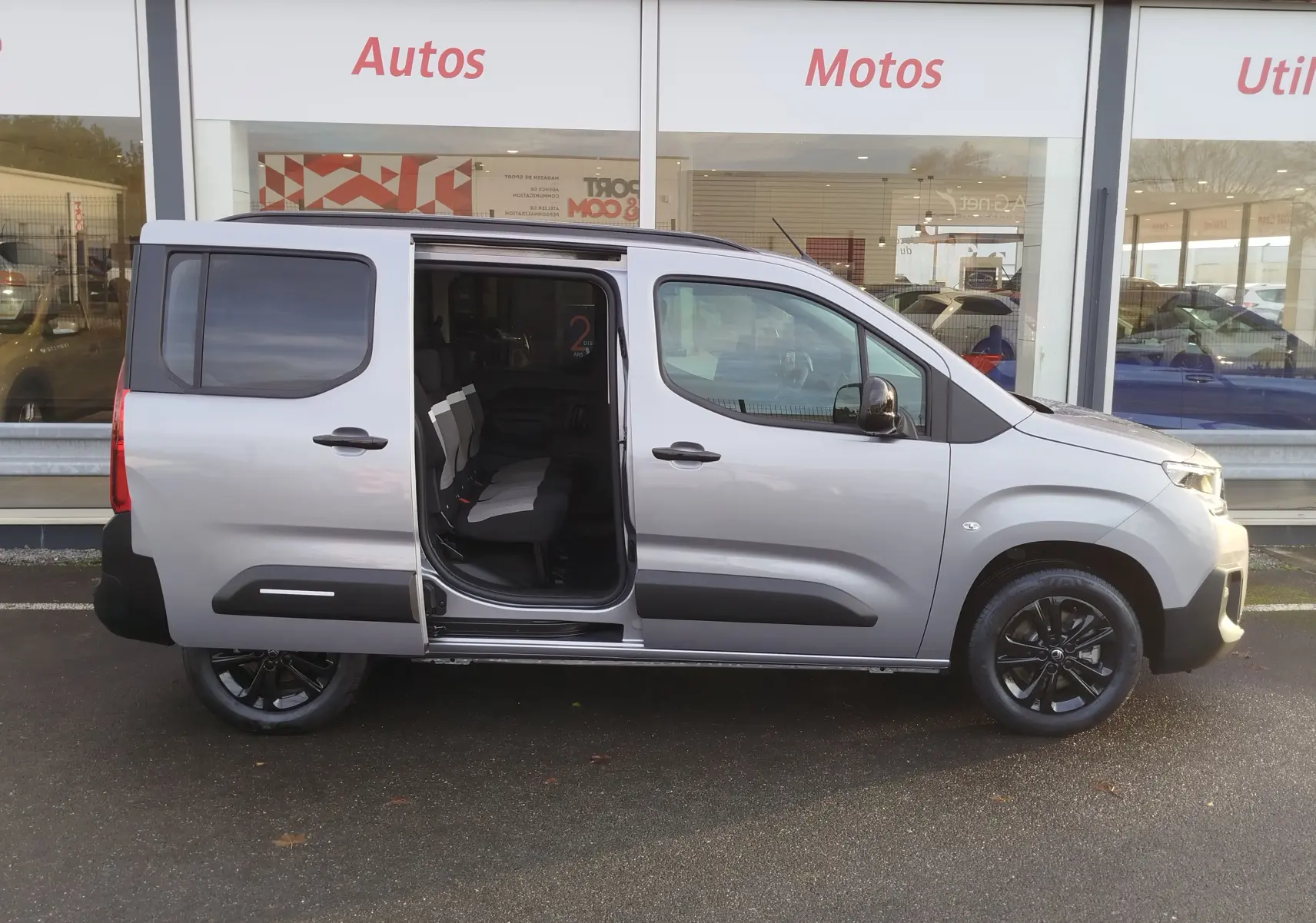Vue latérale droite d'un Citroën Berlingo gris acier 2026 avec porte coulissante ouverte et jantes noires.