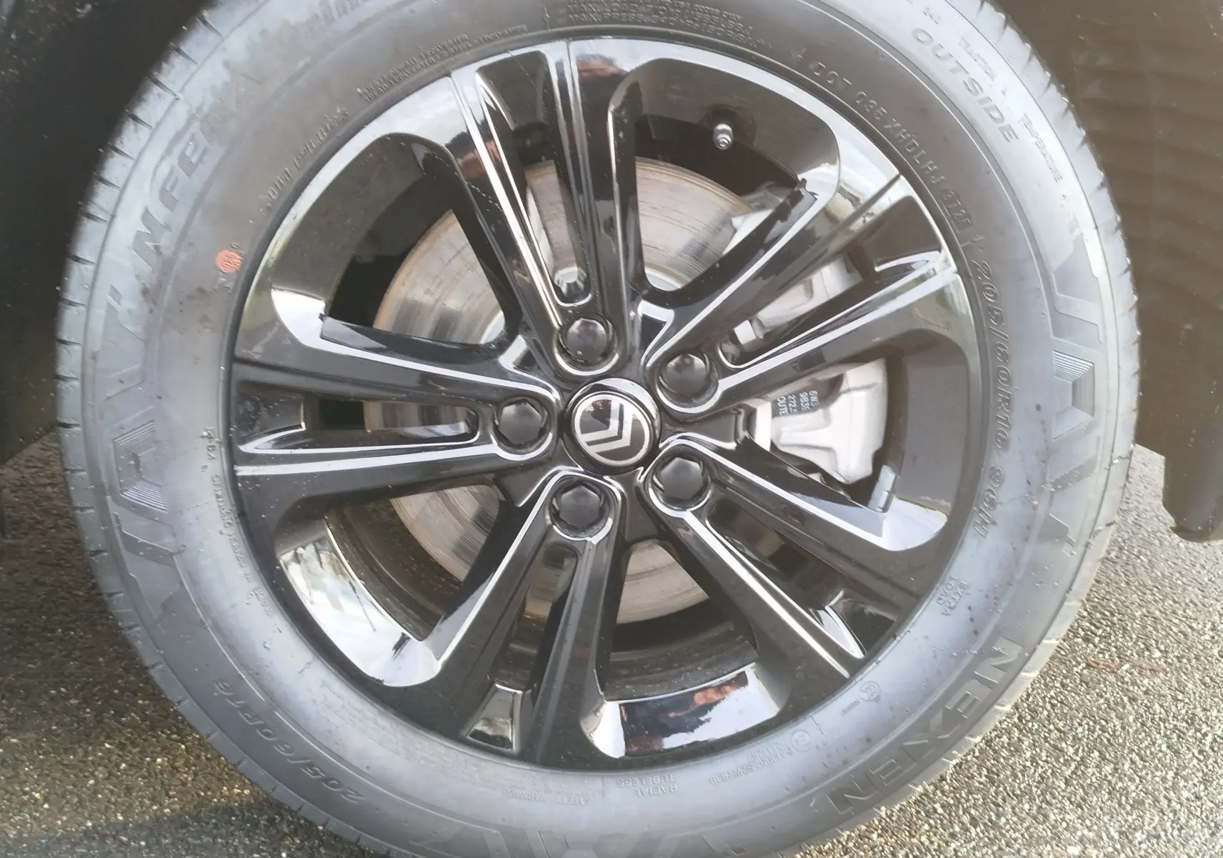 Gros plan sur la roue avant droite du Citroën Berlingo 2026 gris acier avec jante noire brillante et logo Citroën central.