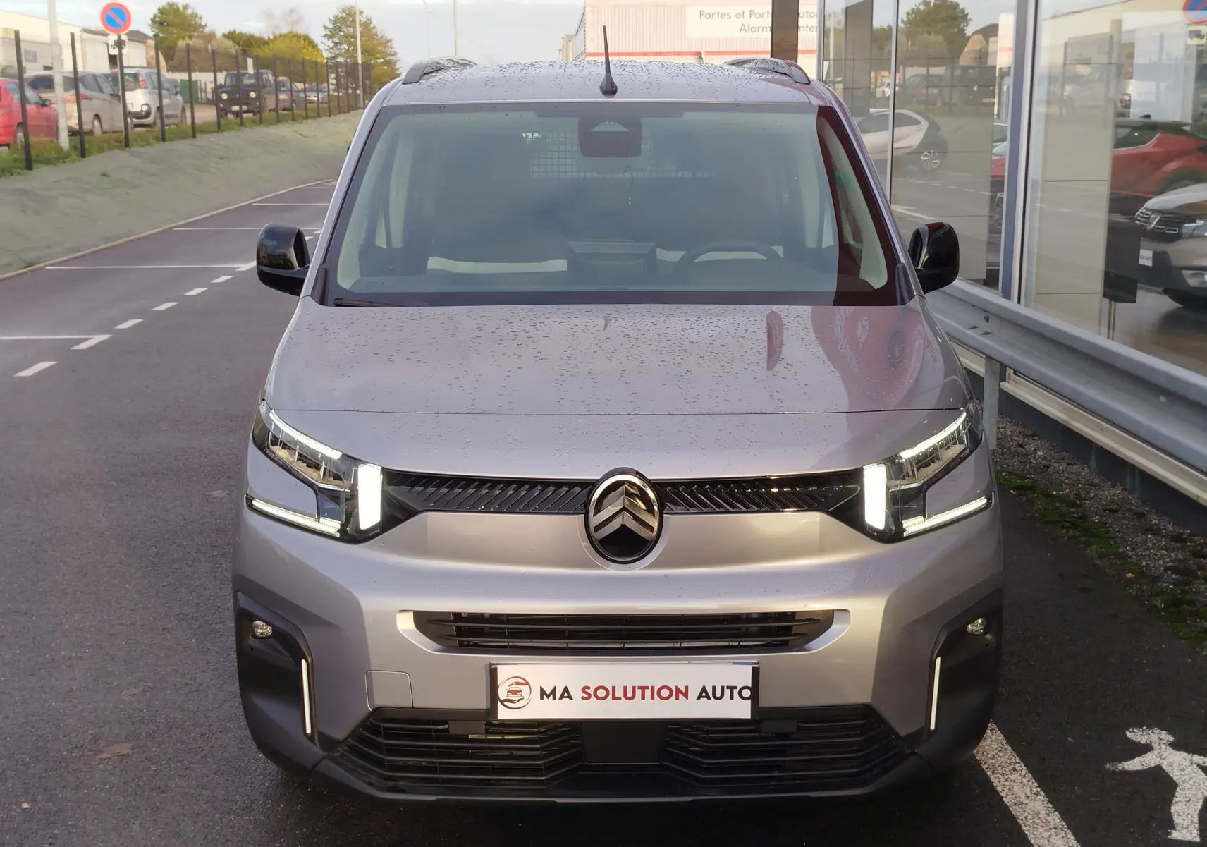 Vue frontale d'un Citroën Berlingo gris acier 2026 avec phares LED allumés et calandre noire brillante.