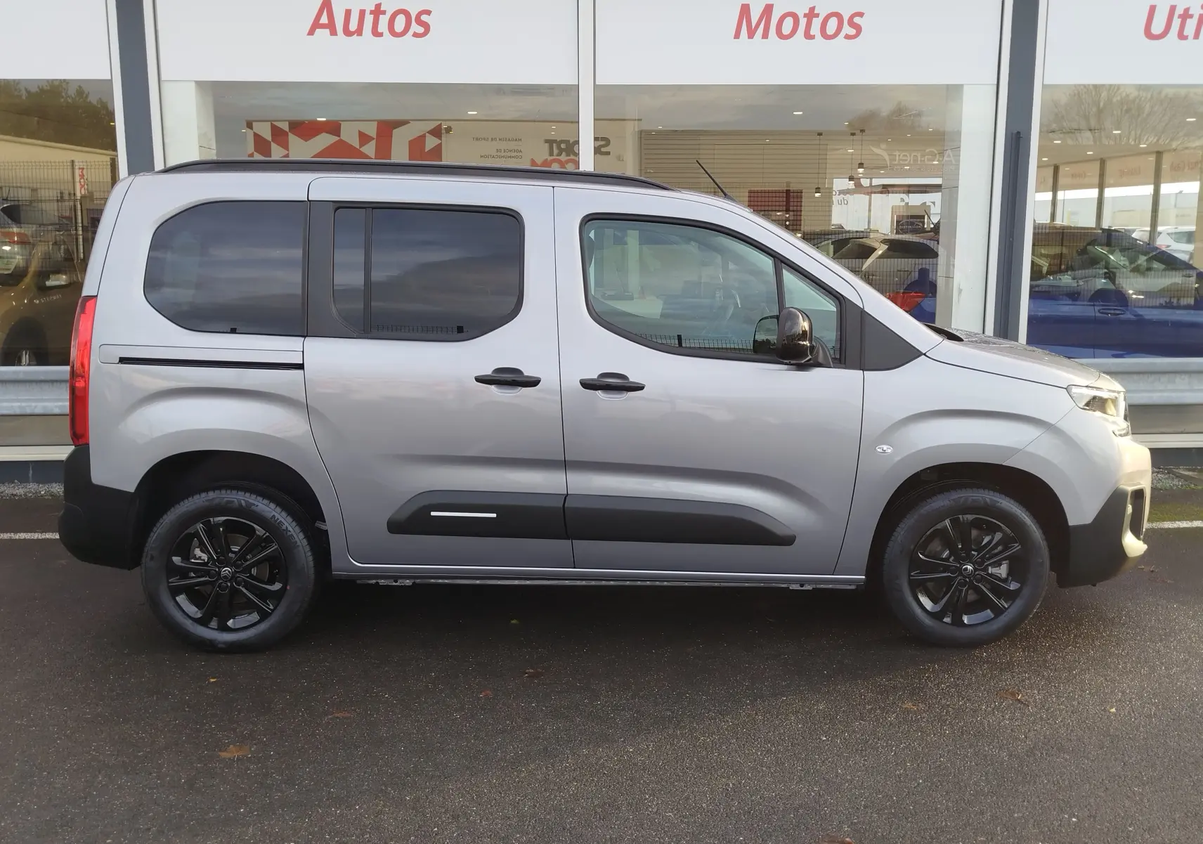 Vue de profil côté droit d'un Citroën Berlingo gris acier avec jantes noires et vitres teintées.
