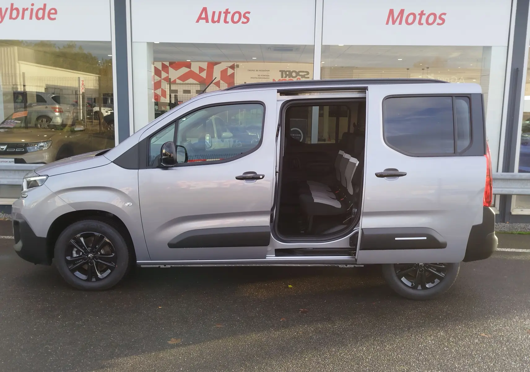 Vue de profil droit d'un Citroën Berlingo gris acier 2026 avec porte coulissante ouverte révélant l'intérieur 5 places.