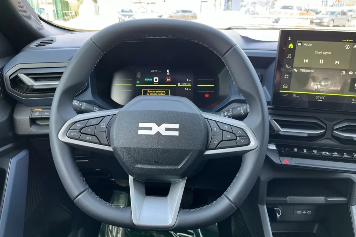 Vue centrée sur le volant cuir du tableau de bord du Dacia Bigster Hybrid 155 Expression Plus avec écran tactile et commandes intégrées.