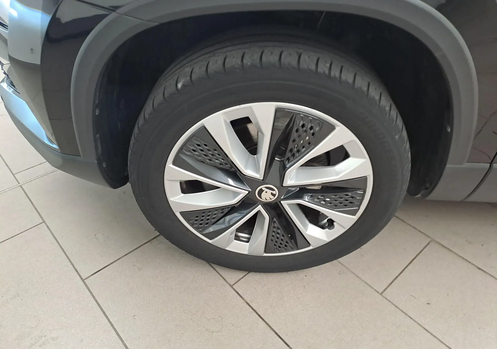 Gros plan sur la roue avant gauche du Skoda Karoq noir Magic Nacré, mettant en valeur la jante au design moderne.
