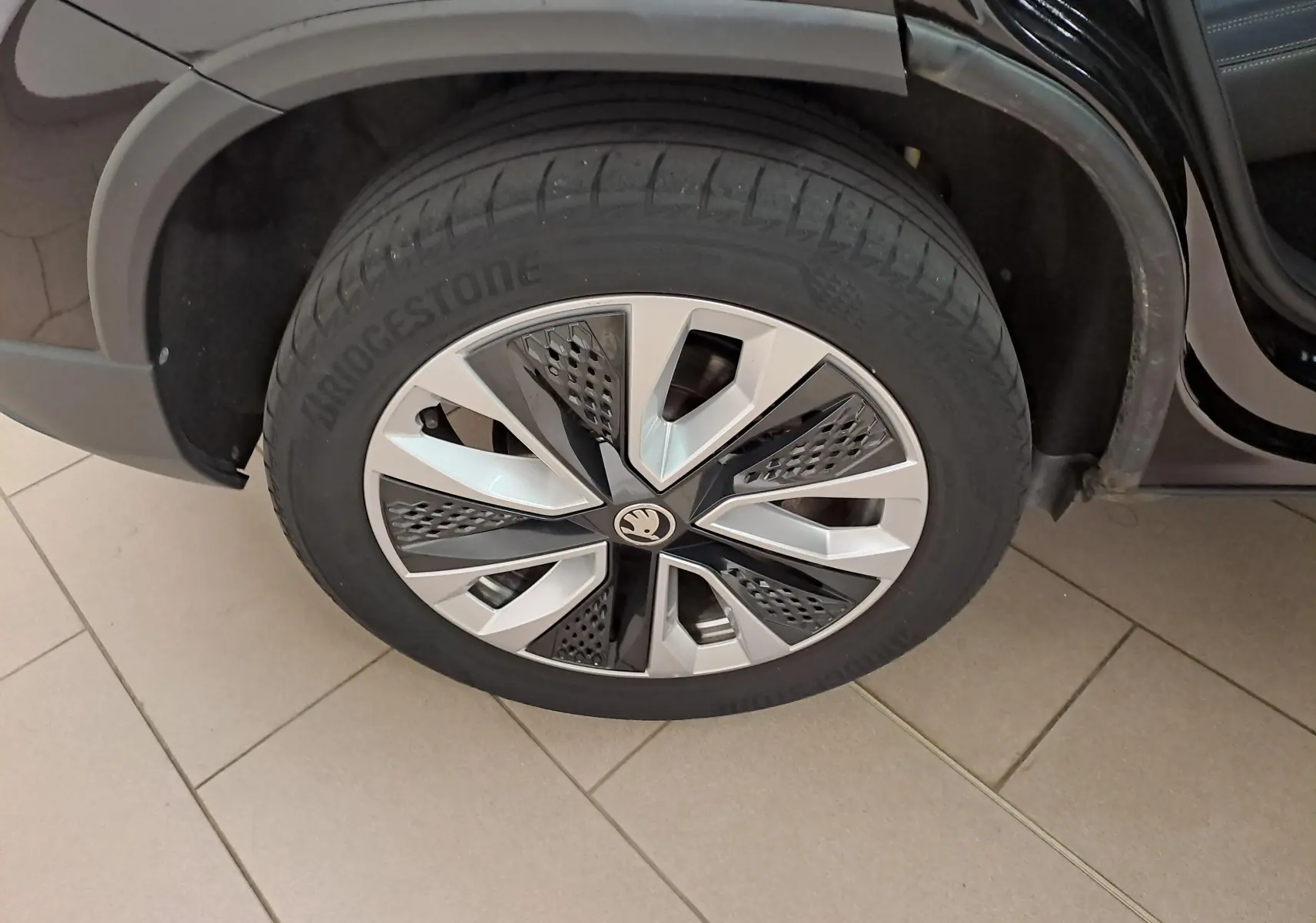 Gros plan sur la roue avant droite du Skoda Karoq noir Magic Nacré, mettant en valeur la jante alliage au design moderne.