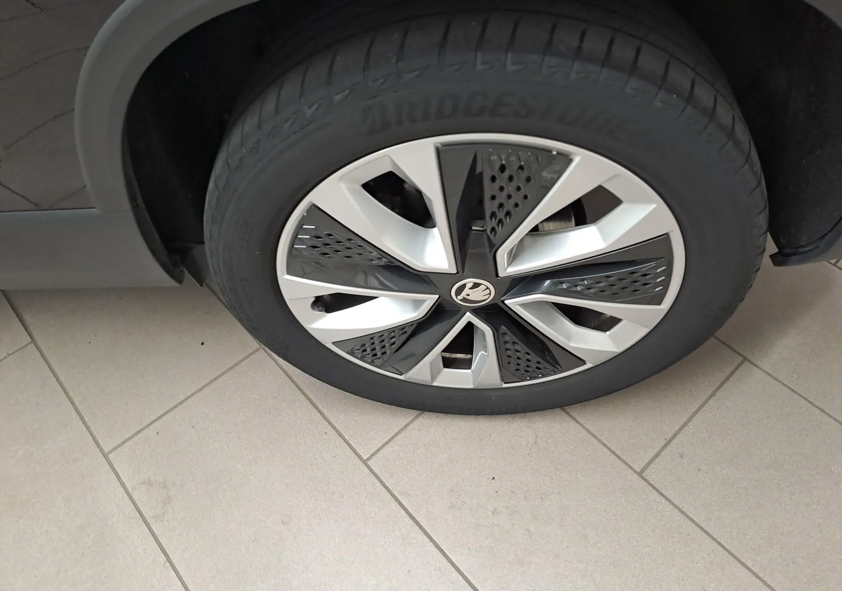 Gros plan sur la roue avant droite du Skoda Karoq noir Magic Nacré, mettant en valeur la jante au design moderne bicolore.