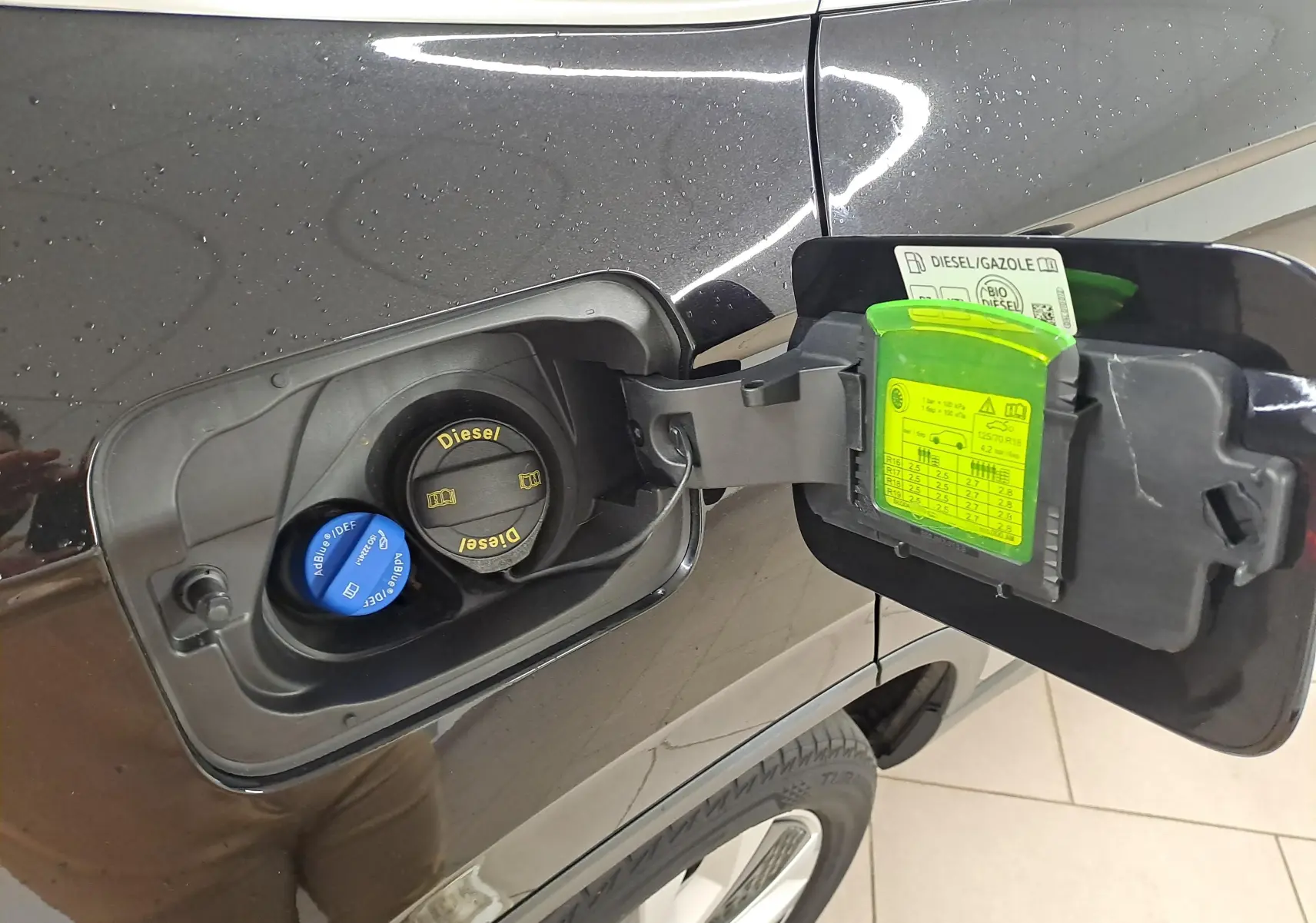 Vue rapprochée de la trappe à carburant côté gauche d’un Skoda Karoq noir Magic Nacré avec bouchons Diesel et AdBlue visibles.