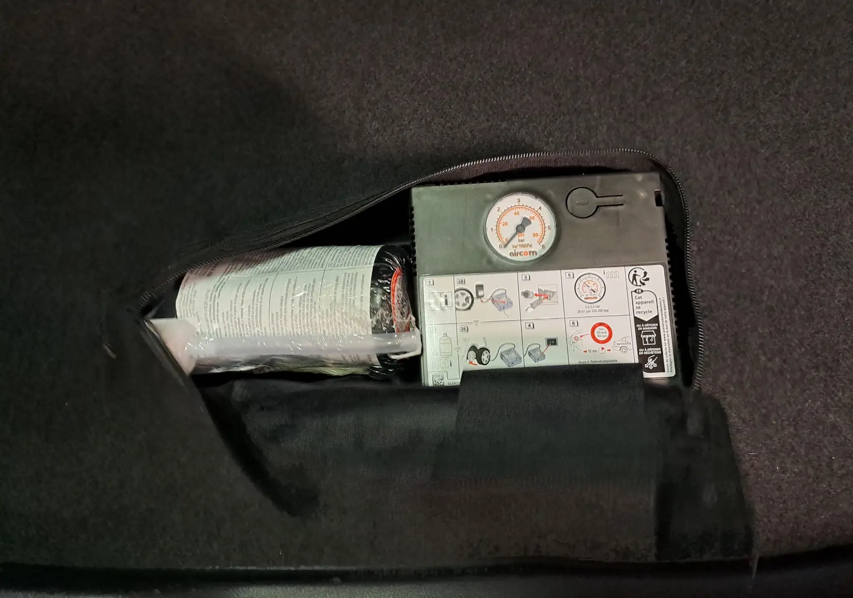 Gros plan sur le compresseur de pneu intégré dans le coffre du Skoda Karoq noir Magic Nacré 2023.