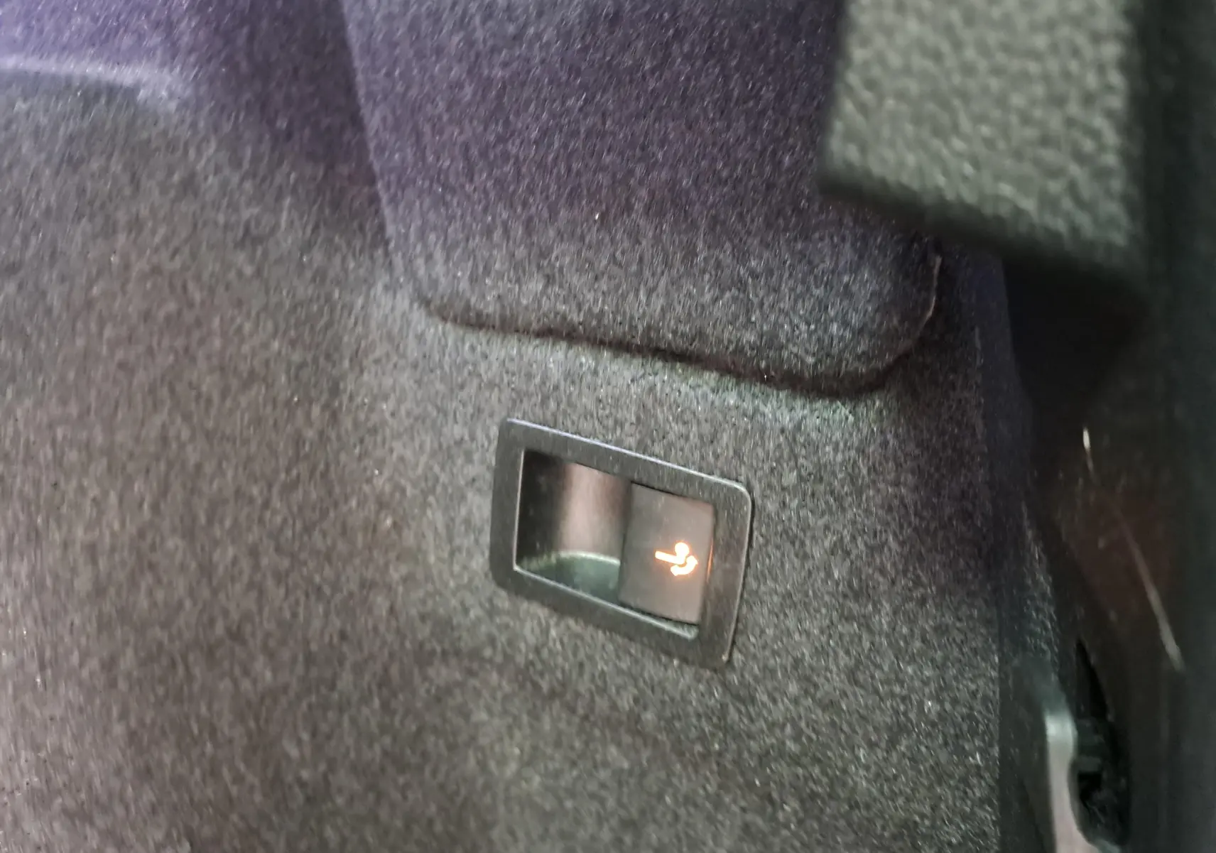 Gros plan sur le bouton d'inclinaison des sièges arrière dans le coffre du Skoda Karoq noir Magic Nacré 2023.