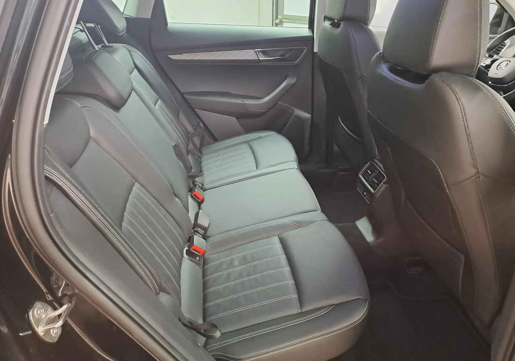 Vue intérieure côté gauche des sièges arrière en cuir noir du Skoda Karoq 2023 avec détails de surpiqûres blanches.