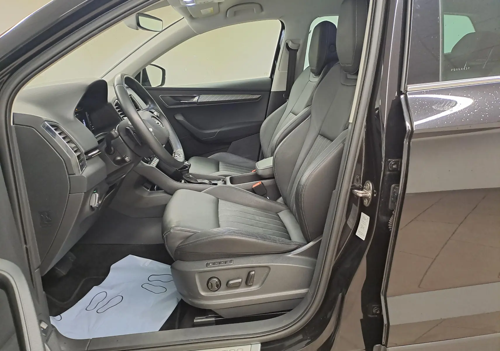 Vue intérieure côté conducteur du Skoda Karoq noir Magic Nacré 2023, avec sellerie cuir et réglages électriques des sièges.