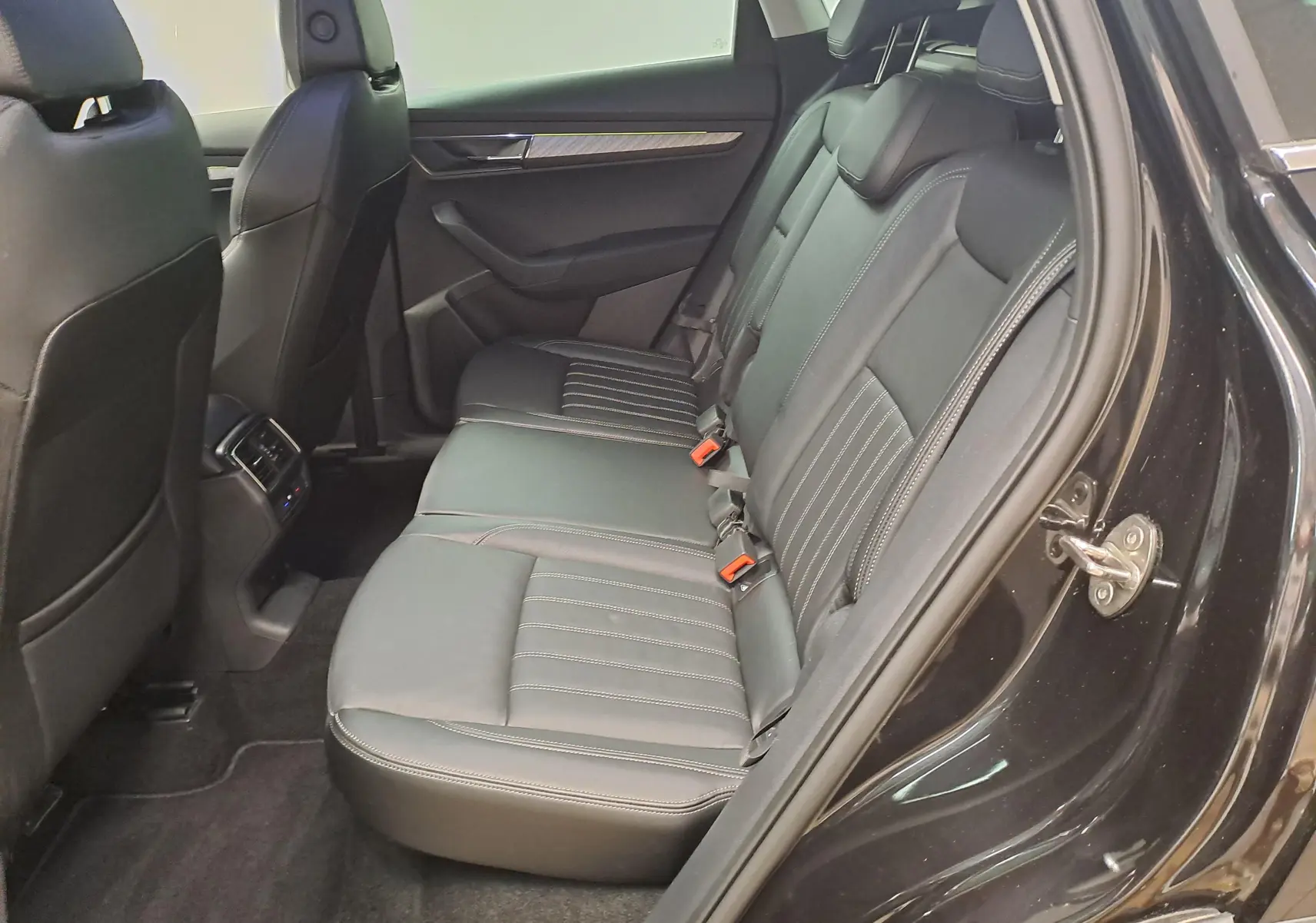 Vue côté droit des sièges arrière en cuir noir du Skoda Karoq 2023 Noir Magic Nacré avec porte ouverte.