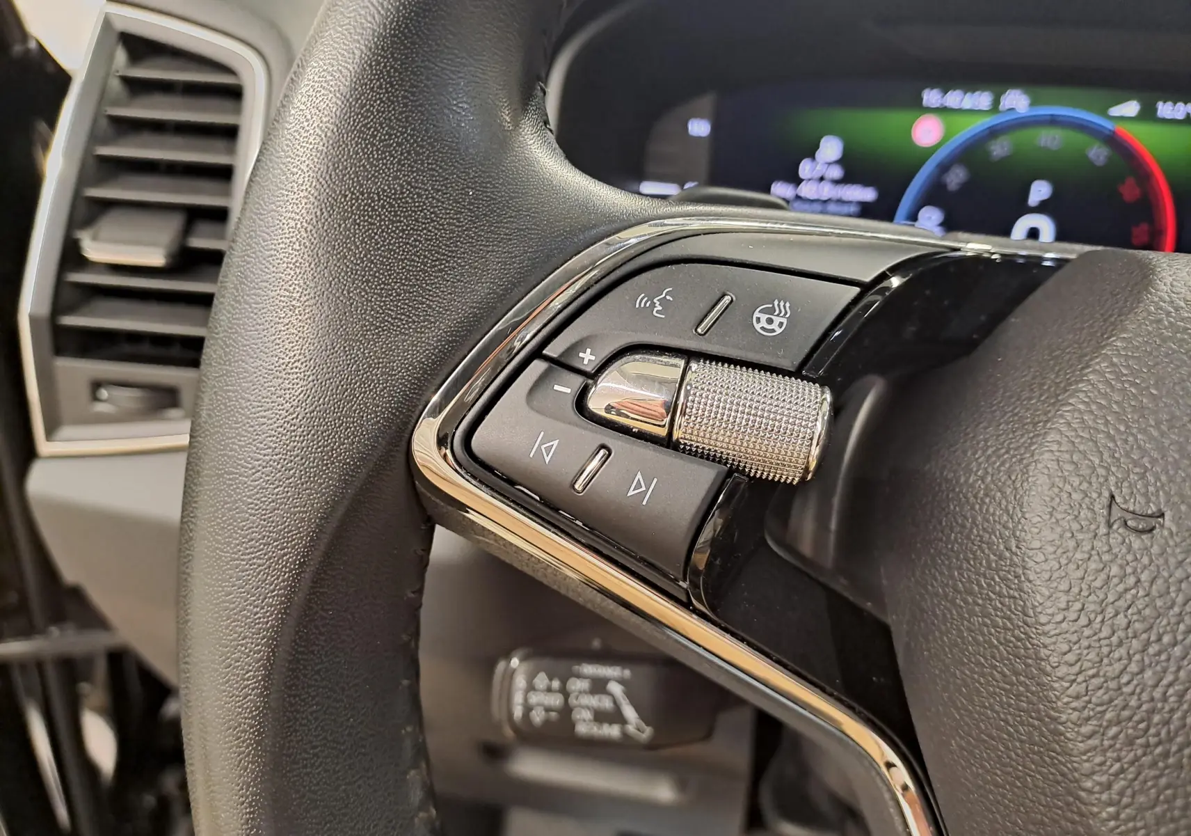 Gros plan sur les commandes gauche du volant du Skoda Karoq 2023, avec finition cuir et tableau de bord numérique flou.