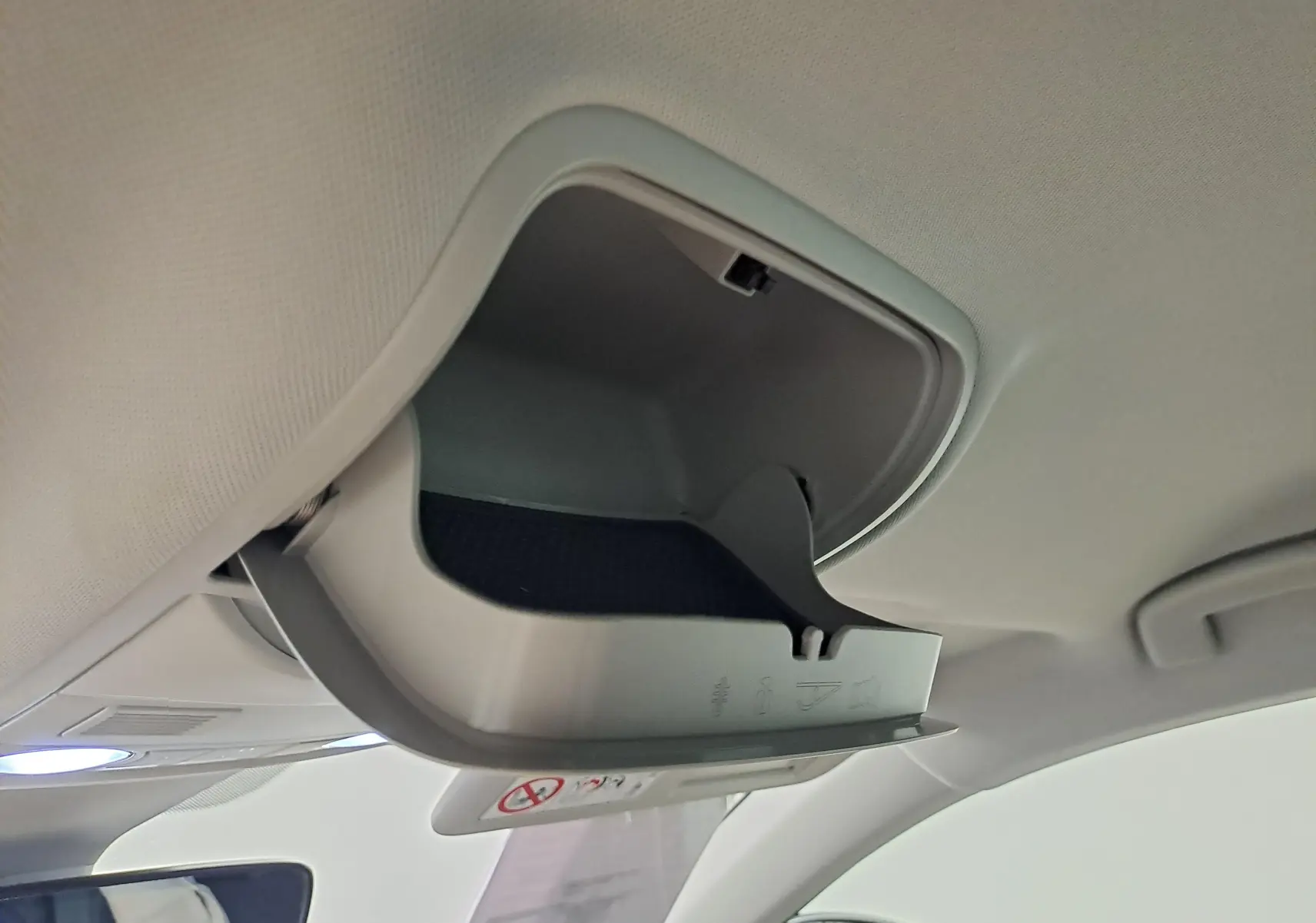Vue intérieure en gros plan du rangement lunettes ouvert sur le plafond du Skoda Karoq noir Magic Nacré 2023.