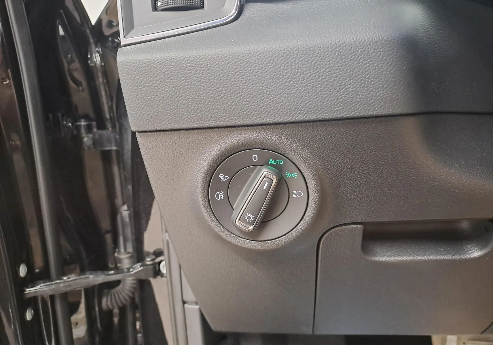 Gros plan sur le bouton de commande des phares du Skoda Karoq noir Magic Nacré, côté gauche intérieur conducteur.
