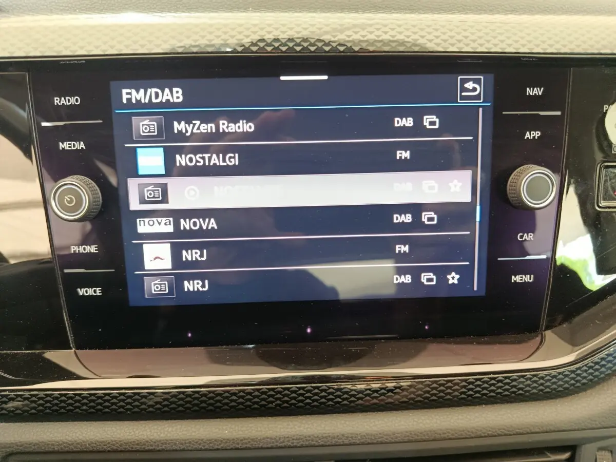 Écran tactile central de la Volkswagen Polo 2023 affichant les stations radio FM/DAB avec commandes autour.