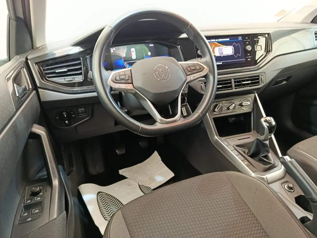 Vue intérieure frontale du volant cuir et alu d'une Volkswagen Polo 2023 avec tableau de bord digital et écran tactile.