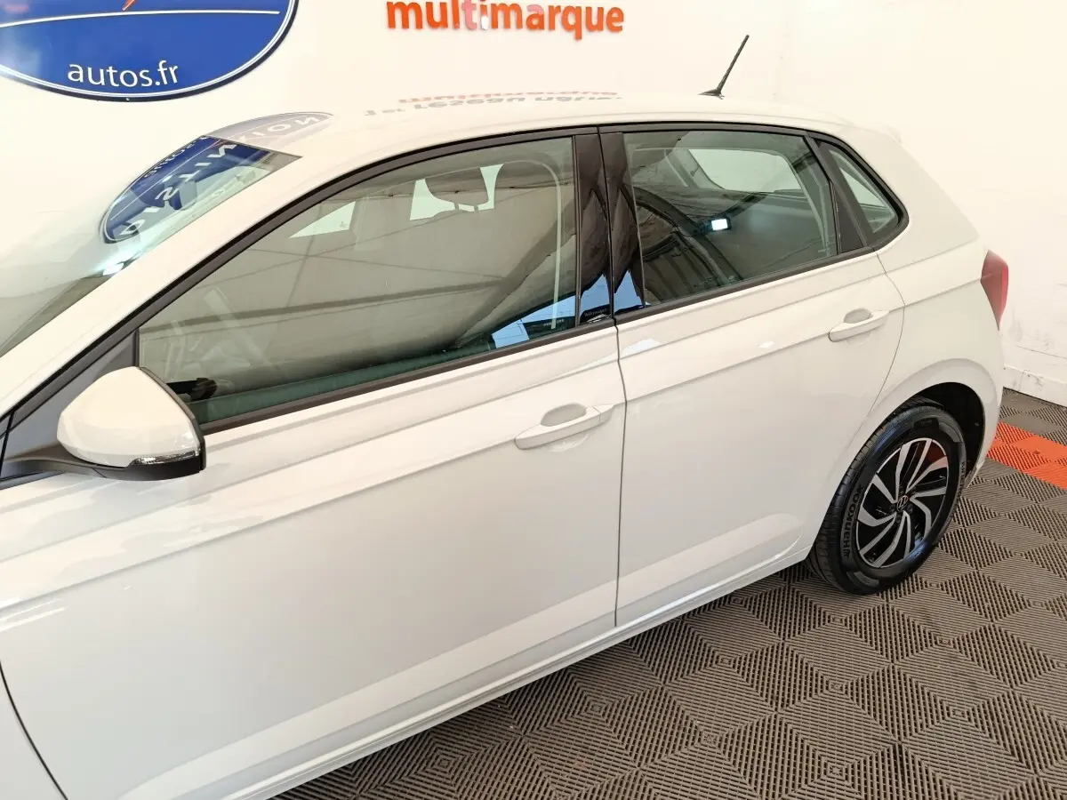 Vue latérale droite d'une Volkswagen Polo gris clair avec jantes alliage et rétroviseurs blancs.