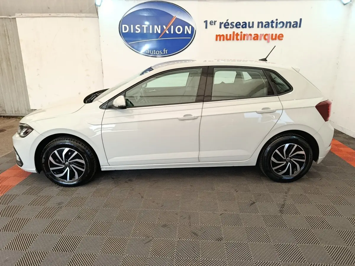 Vue de profil côté gauche d'une Volkswagen Polo 2023 gris clair avec jantes alliage noires et blanches.