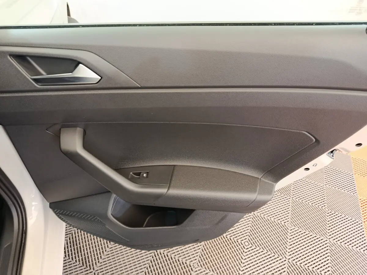 Vue intérieure de la porte avant gauche d'une Volkswagen Polo gris clair, avec poignée et bouton de verrouillage.