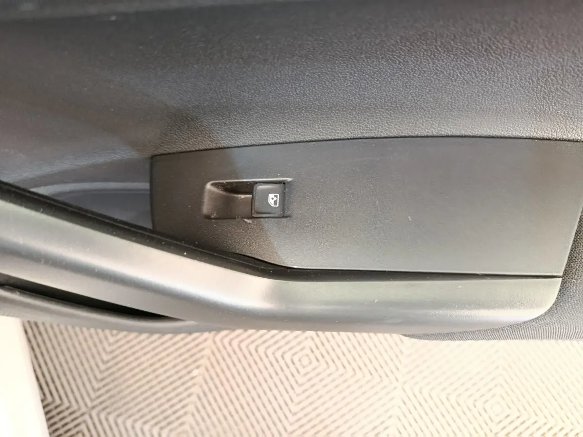 Gros plan sur le bouton de verrouillage centralisé sur la porte intérieure côté conducteur d'une Volkswagen Polo gris clair.