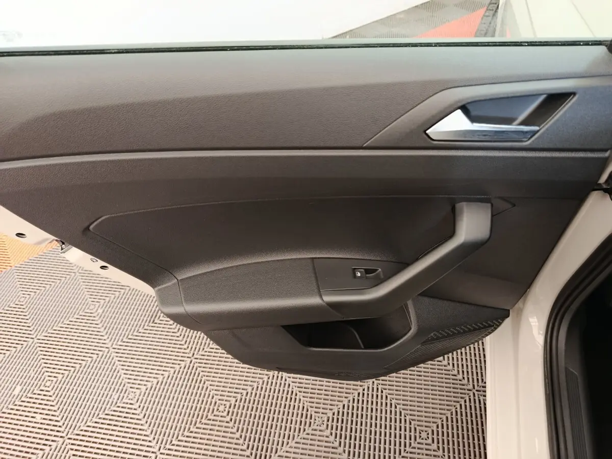 Vue rapprochée de la porte intérieure côté conducteur de la Volkswagen Polo 2023, avec garniture noire et poignée angulaire.