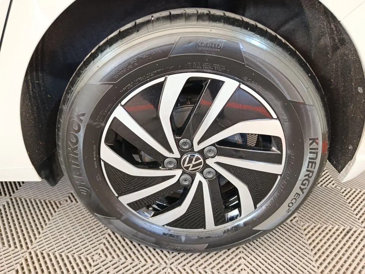 Gros plan sur la roue avant droite d'une Volkswagen Polo gris clair avec jante alliage noire et argentée.
