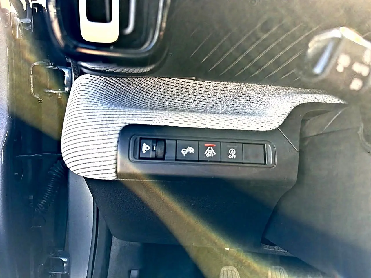 Vue rapprochée des commandes de sécurité côté gauche d’un Citroën C3 2025, tissu gris et plastique noir.