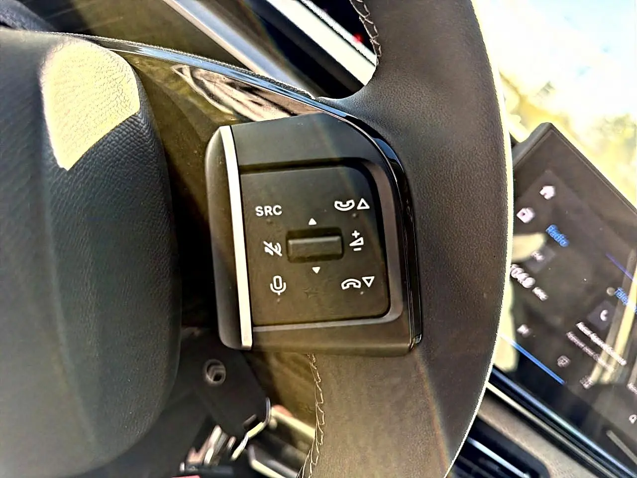 Gros plan sur les commandes audio au volant de la Citroën C3 2025, avec écran tactile en arrière-plan.
