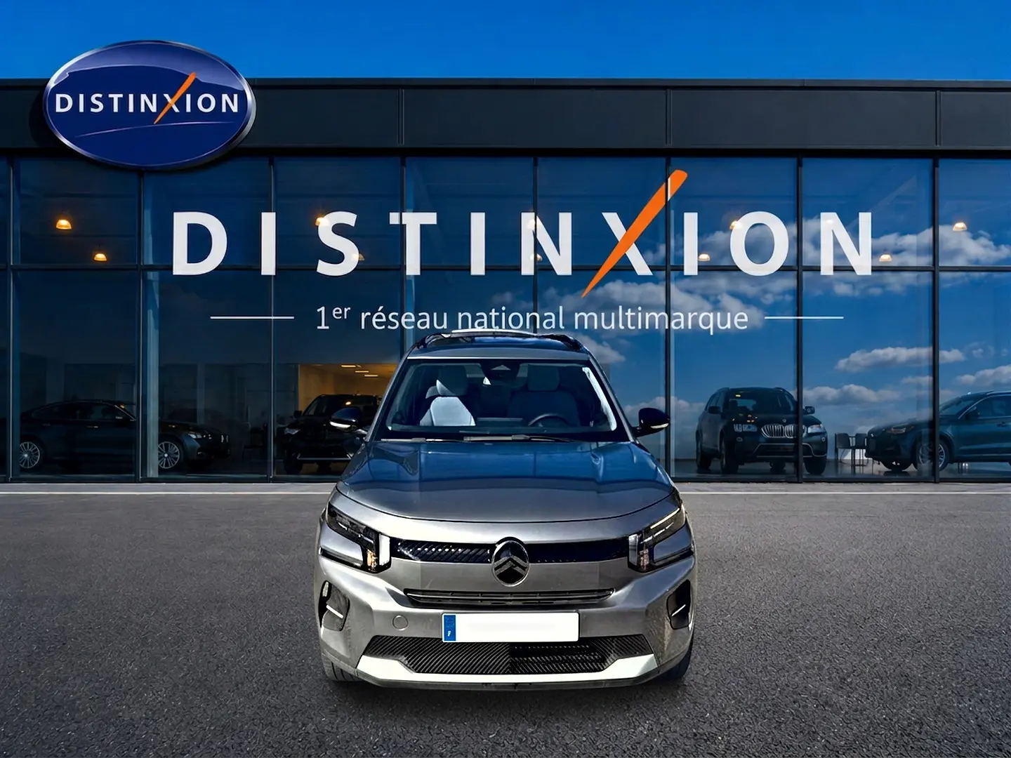 Vue frontale d'une Citroën C3 gris mercure 2025, avec phares LED et calandre moderne, devant un showroom Distinxion.