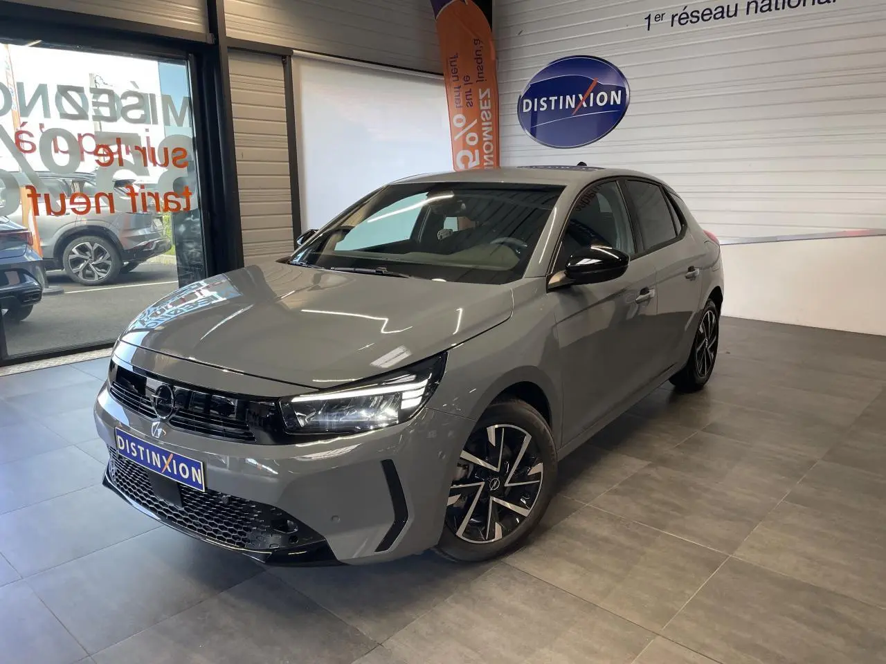 Opel Corsa gris Grafik vue 3/4 avant droit en intérieur avec calandre noire et jantes alliage 16 pouces.