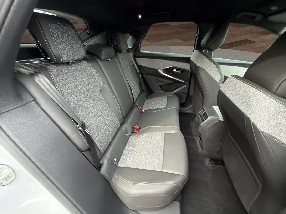 Vue intérieure arrière côté gauche du Peugeot 3008 2025 blanc, sièges bi-matière cuir et tissu gris clair.