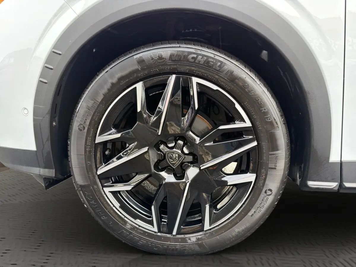 Gros plan sur la roue avant droite du Peugeot 3008 blanc, mettant en valeur la jante noire brillante au design moderne.
