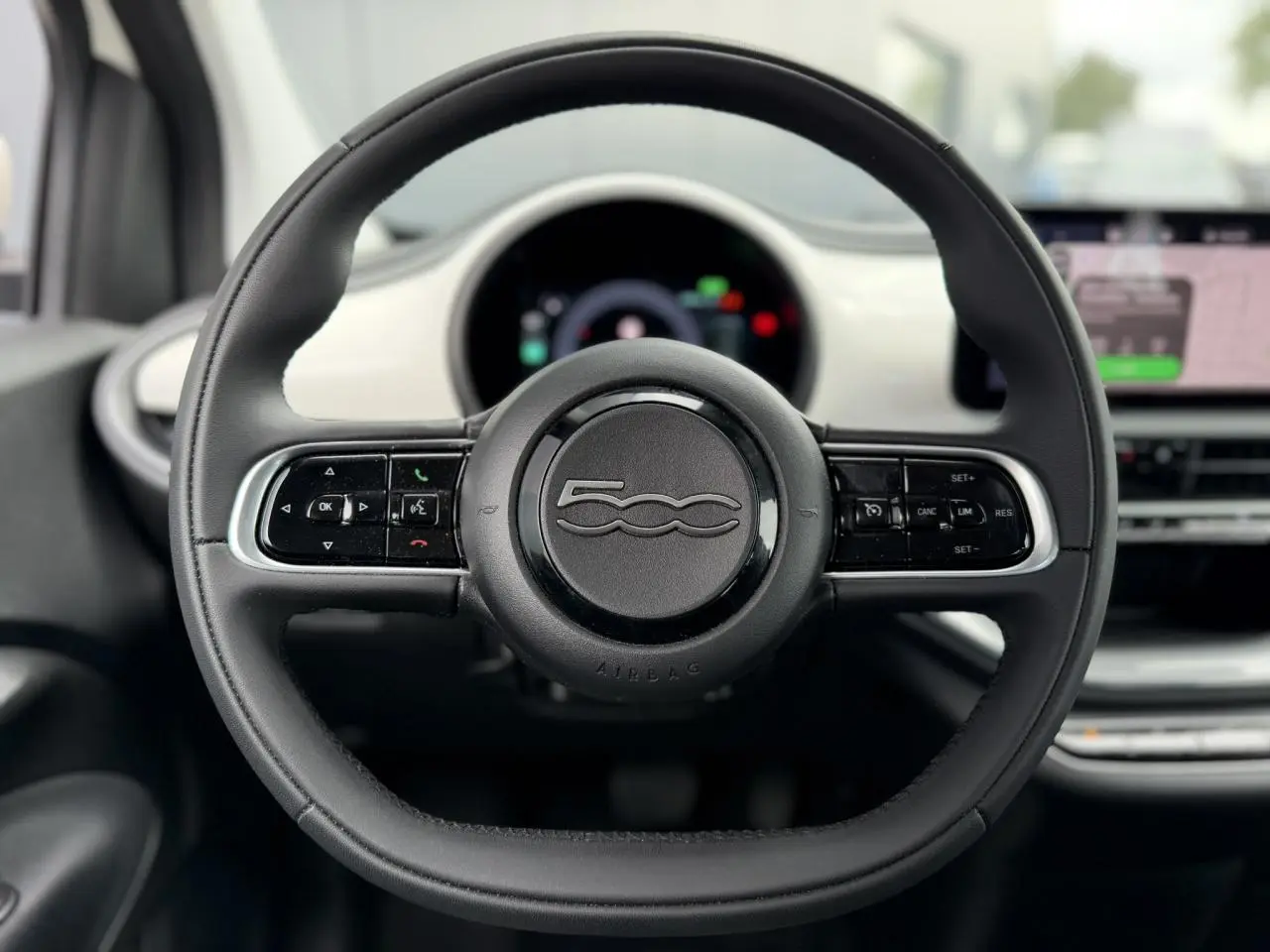 Vue rapprochée du volant noir Soft-Touch de la Fiat 500 électrique 2024 avec tableau de bord blanc Arctic.