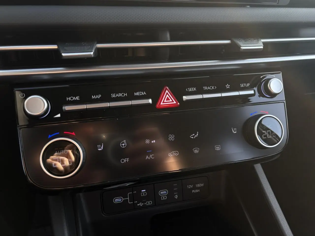 Vue rapprochée de la console centrale du Hyundai Tucson 2025, affichant les commandes tactiles et boutons de climatisation.