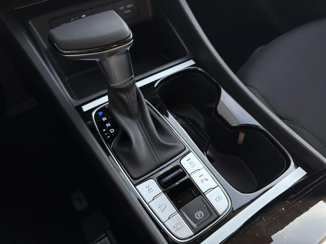 Gros plan sur la console centrale du Hyundai Tucson 2025 avec levier de vitesses cuir et commandes de conduite.