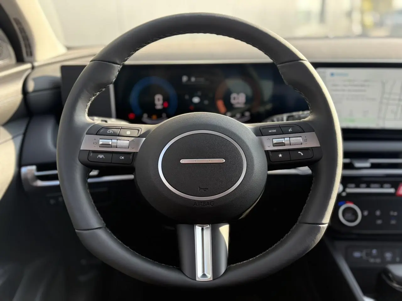 Volant en cuir noir de la Hyundai Tucson 2025 avec commandes intégrées et tableau de bord numérique en arrière-plan.