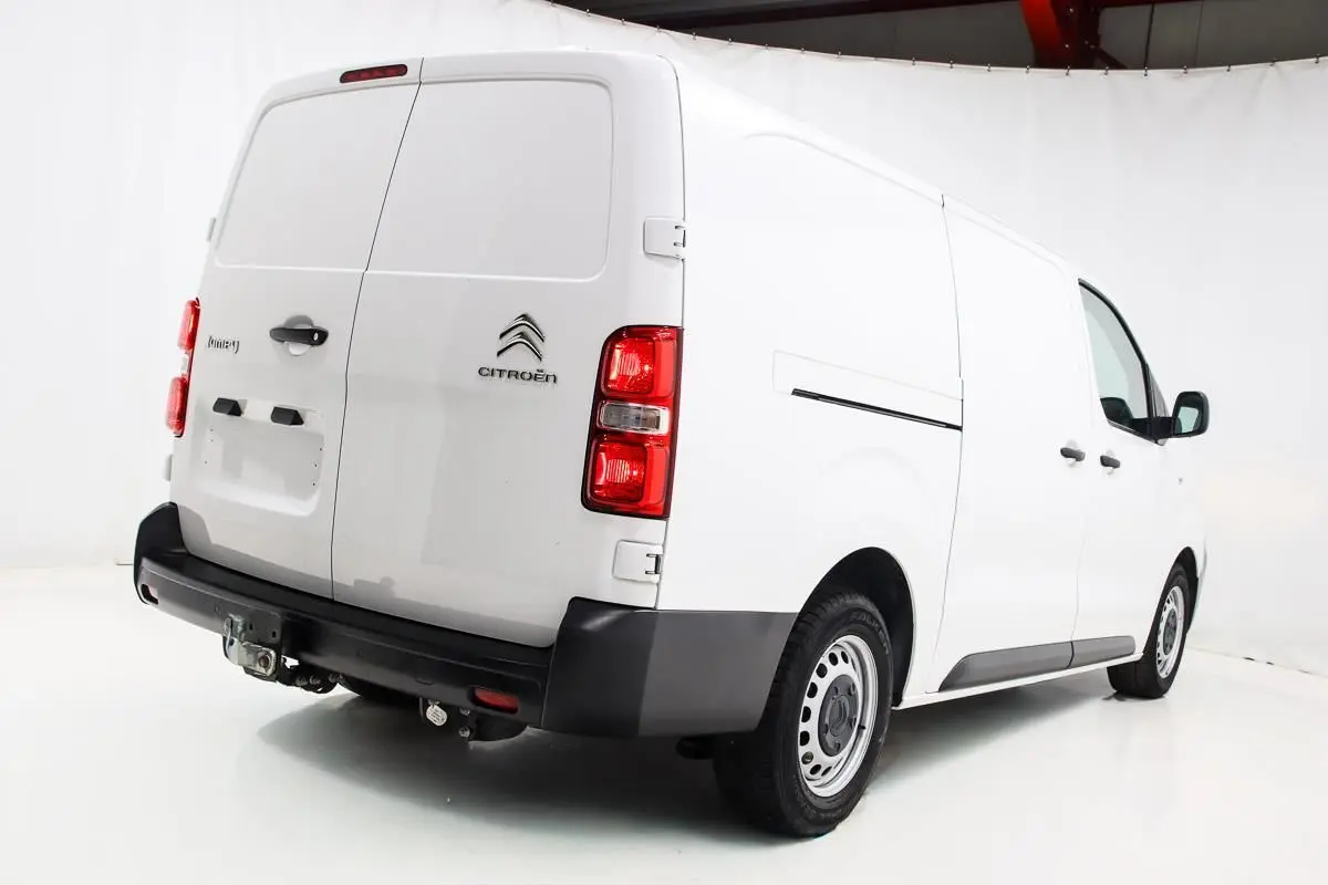 Vue 3/4 arrière droite d'un fourgon Citroën Jumpy blanc avec attelage et portes arrière battantes.