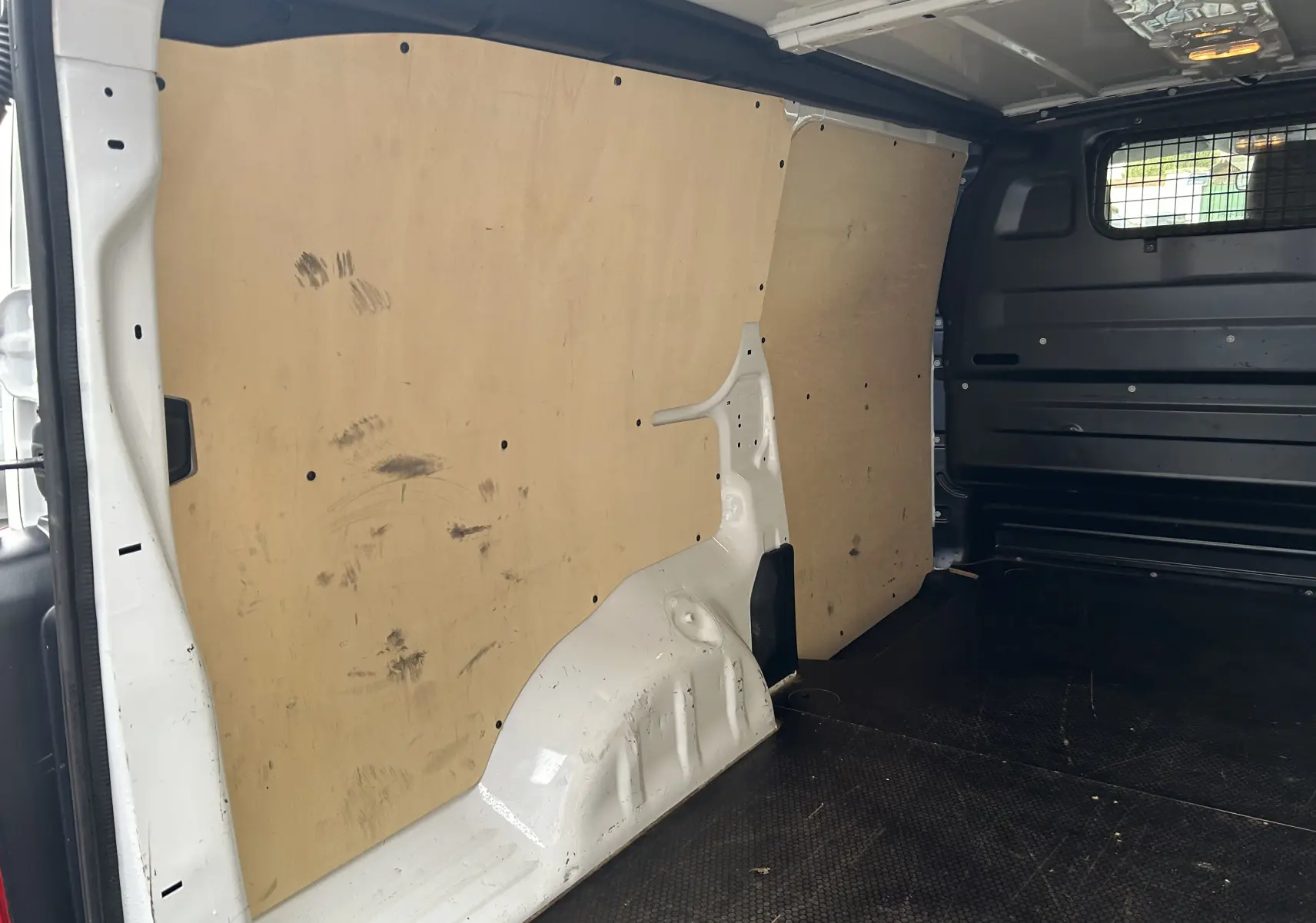 Vue intérieure du fourgon blanc Citroën Jumpy XL 2019, montrant la cloison bois et le plancher noir antidérapant.