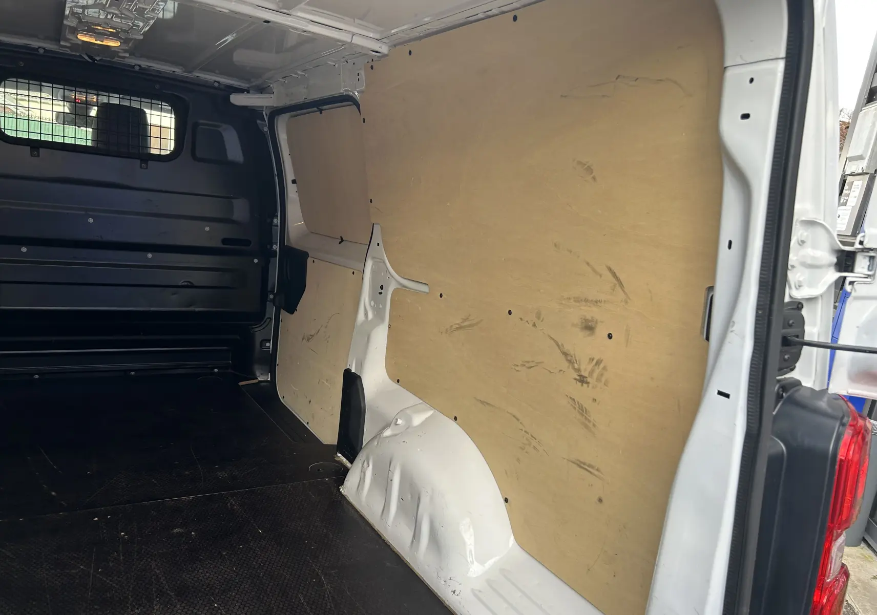 Vue intérieure côté droit du fourgon blanc Citroën Jumpy XL 2019, montrant la cloison bois et le plancher noir.