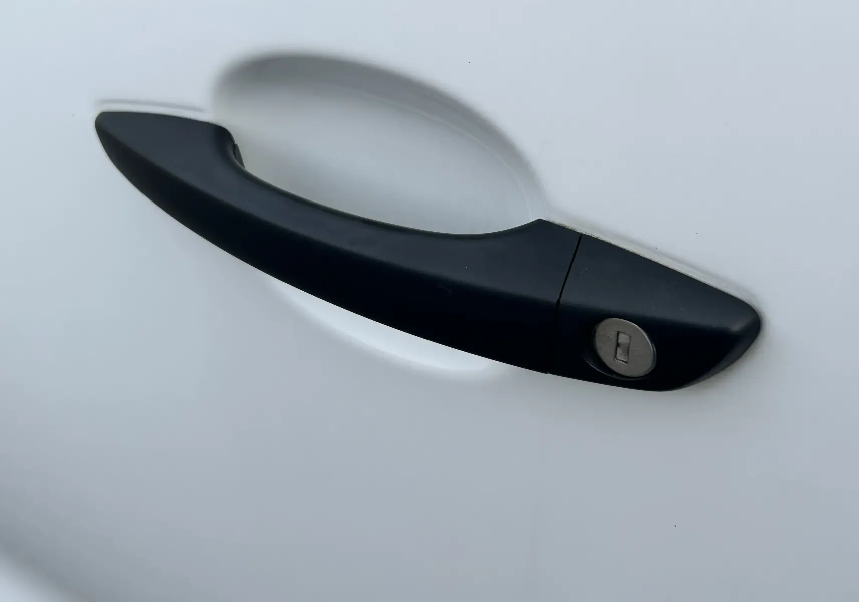 Poignée de porte noire avec serrure sur la portière blanche d'un Citroën Jumpy Fourgon XL 2019.