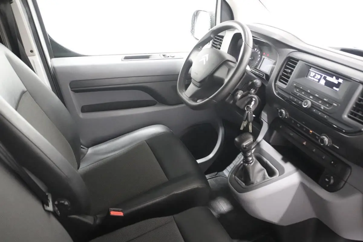 Vue intérieure côté conducteur du Citroën Jumpy blanc, montrant le volant, tableau de bord et levier de vitesse manuel.