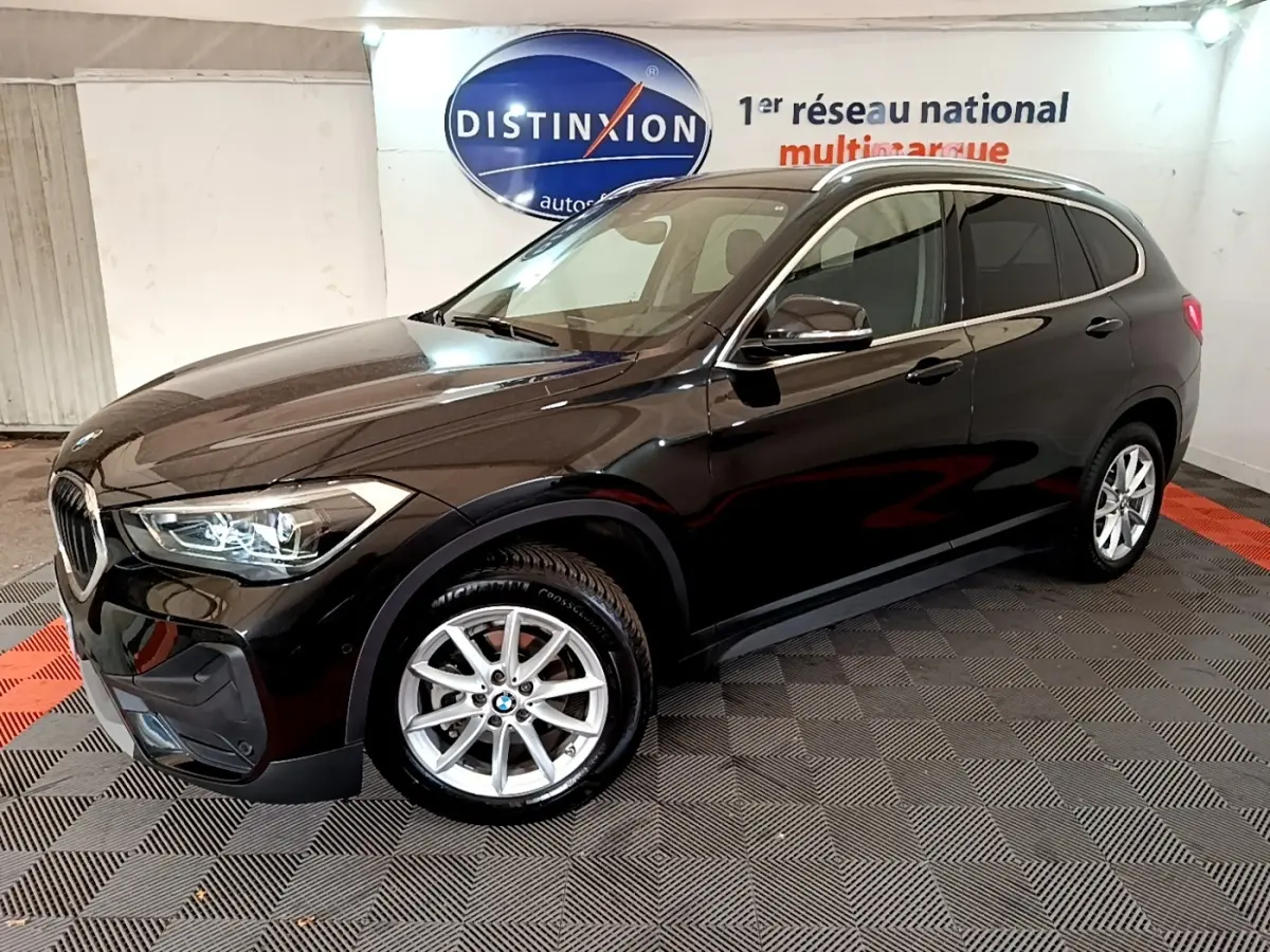 BMW X1 noir vue 3/4 avant droit, mettant en valeur ses phares LED et jantes alliage argentées.