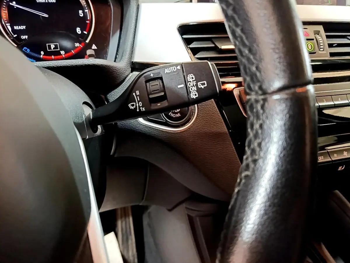 Gros plan sur le commodo d’essuie-glace côté gauche du tableau de bord noir du BMW X1 2020 sDrive16d Business Design.