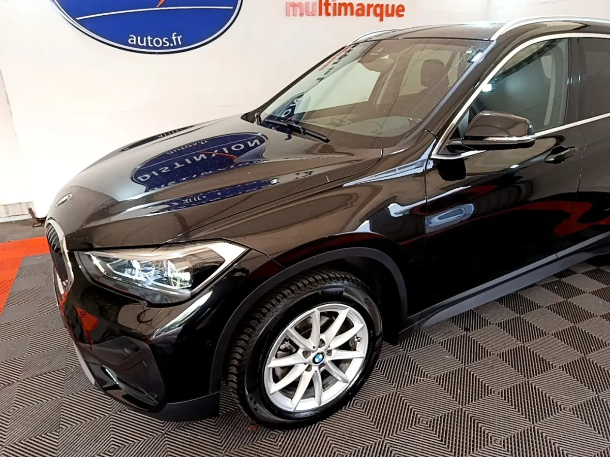 BMW X1 noir vue 3/4 avant droit mettant en valeur ses phares LED et jantes alliage argentées.