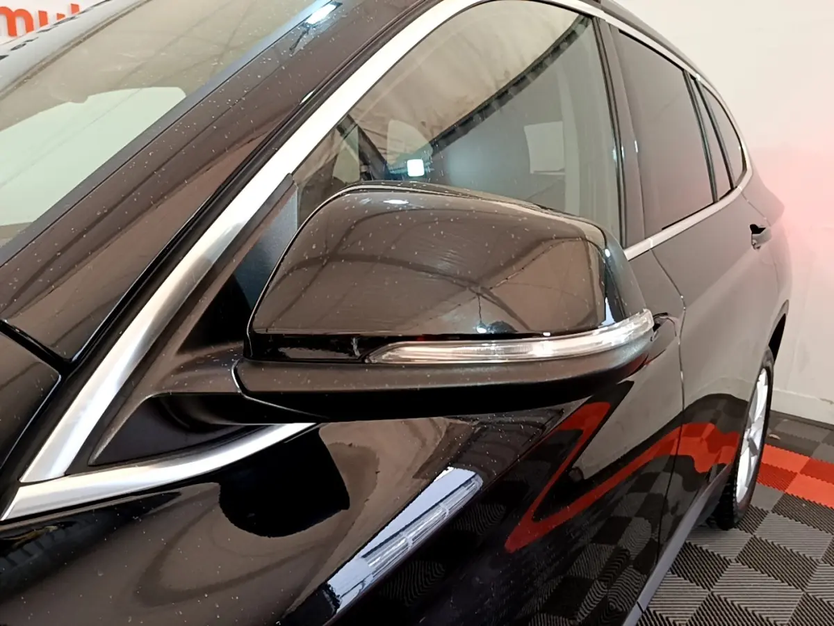 Gros plan sur le rétroviseur côté gauche noir brillant du BMW X1 sDrive16d Business Design 2020.