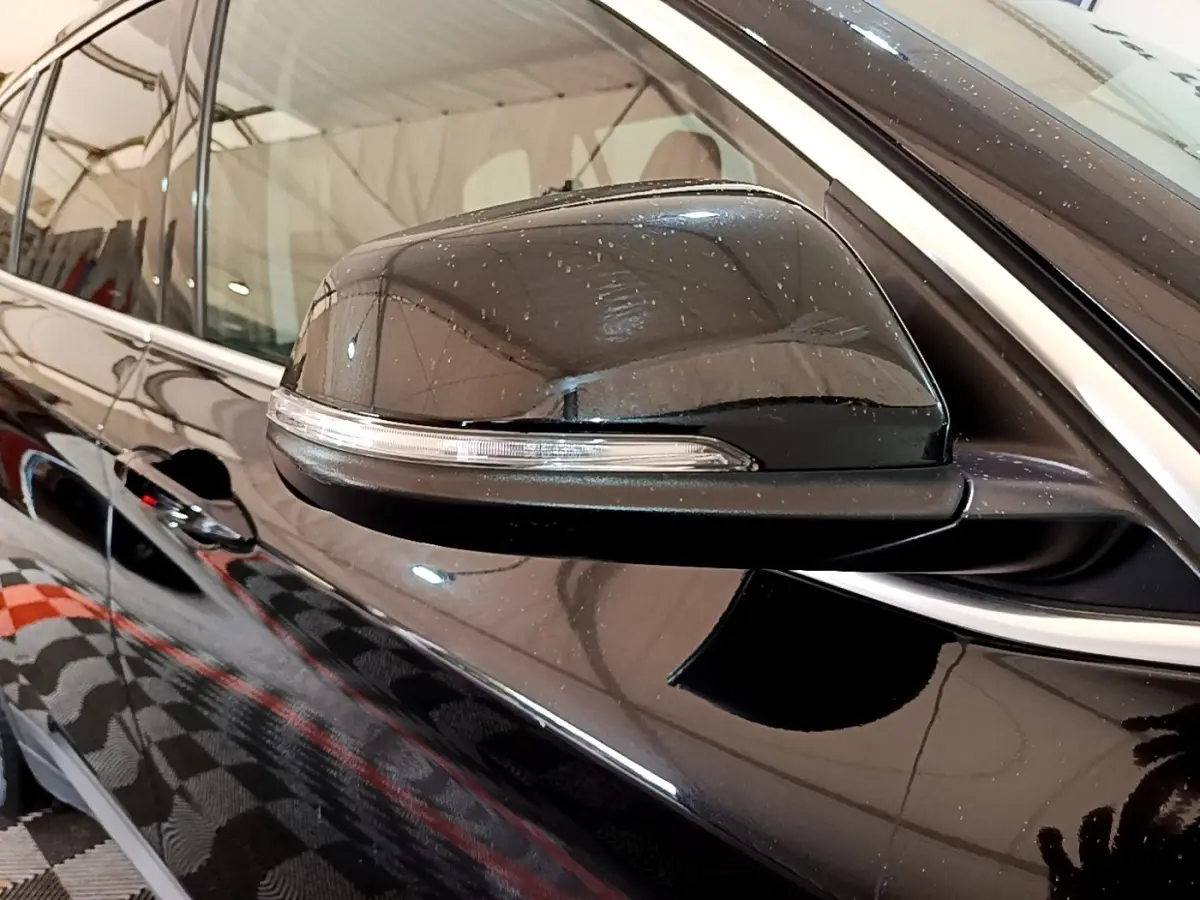 Gros plan sur le rétroviseur côté gauche noir brillant de la BMW X1 sDrive16d Business Design 2020.