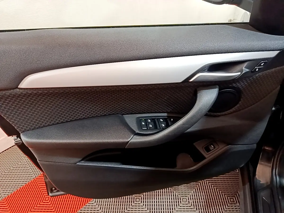 Détail de la porte côté conducteur noire du BMW X1 2020 avec commandes de vitres et poignée intégrée.